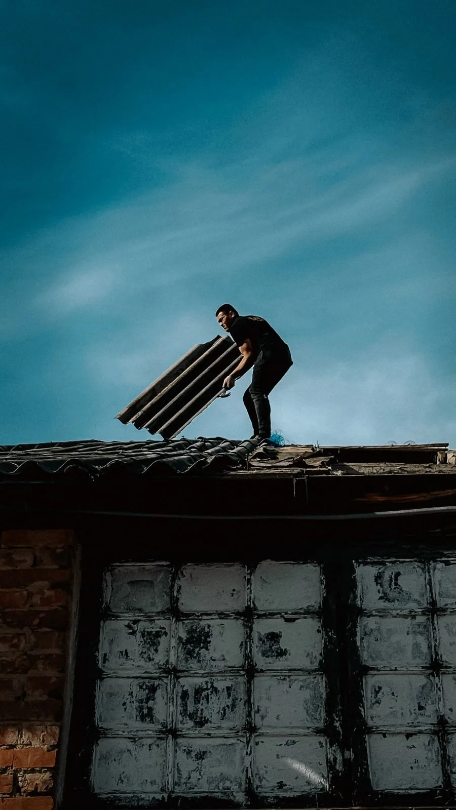 Roofer repairing roof sheets on a pitched roof