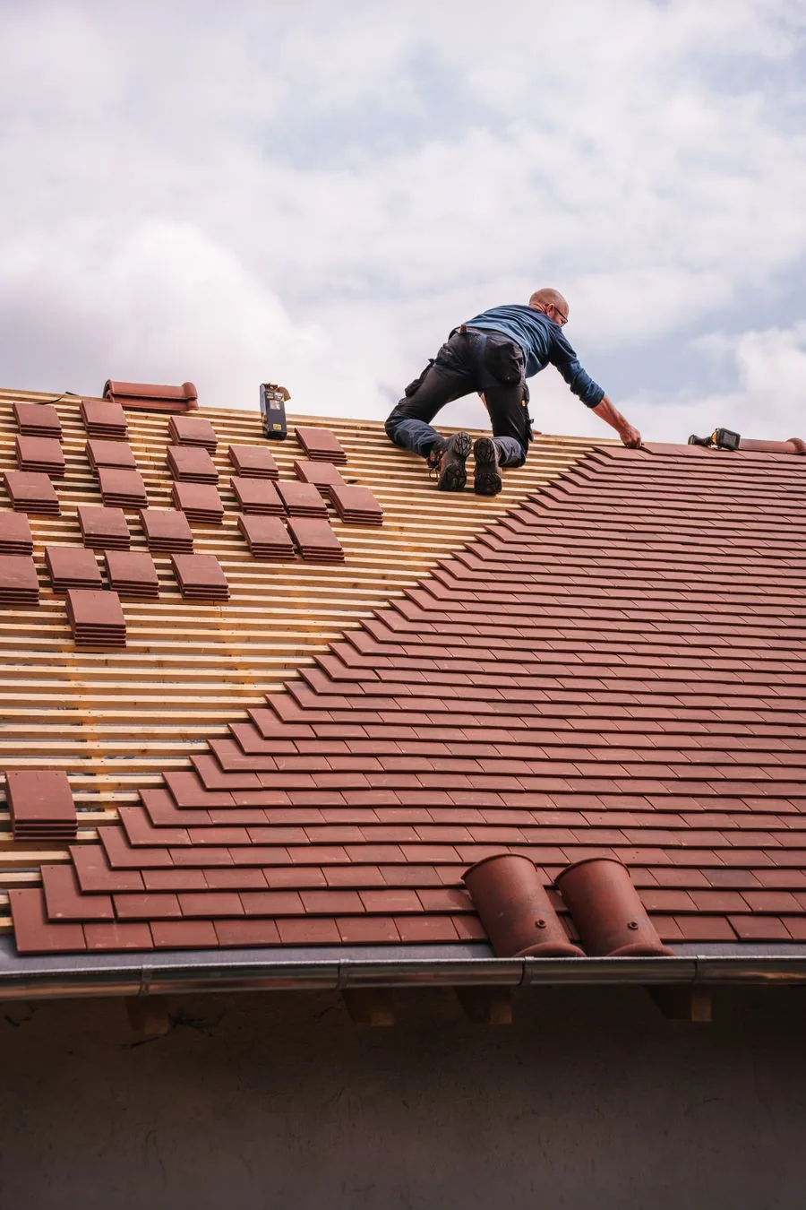 Roofer fitting clay tiles on a pitched roof